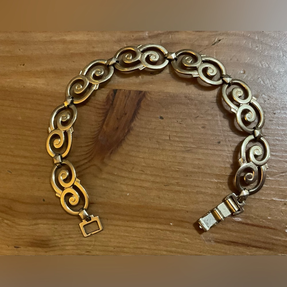We Richard: Symmetrical scroll about/approximately 7” inches gold tone.bracelet